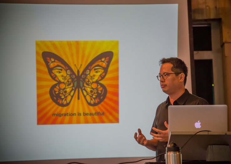 Jeff Chang discussing the "Migration is Beautiful" campaign; campaign image created by Favianna Rodriguez. Photo: Melisa Cardona, 2015. 
